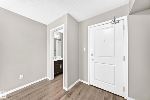 Wood-finish flooring, light gray wall paint, and white trim - #322 148 Ebbers Bv Nw, Edmonton, AB - Indoor Photo Showing Other Room