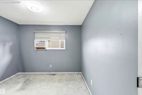 Window with integrated air conditioning unit, ceiling-mounted light fixture, and wall-to-wall carpeting - 13604 90A Street Nw, Edmonton, AB - Indoor Photo Showing Other Room