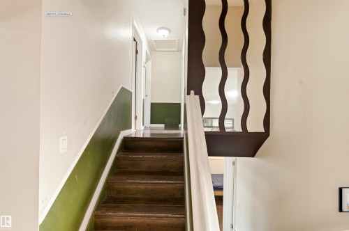 Hardwood staircase featuring a white handrail and decorative wall paneling - 13604 90A Street Nw, Edmonton, AB - Indoor Photo Showing Other Room