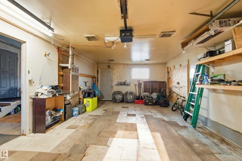 Garage space featuring an overhead garage door opener, overhead lighting, and built-in shelving - 13604 90A Street Nw, Edmonton, AB - Indoor Photo Showing Garage