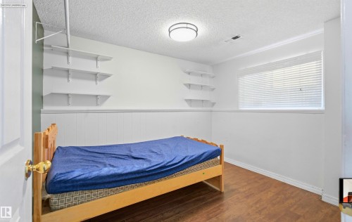 Wood-finish flooring with white baseboards, white wall paneling, and built-in shelving - 13604 90A Street Nw, Edmonton, AB - Indoor Photo Showing Bedroom