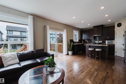 Open-concept living area with wood-finish flooring, recessed lighting, and large windows - 3843 Agar Green Sw, Edmonton, AB - Indoor