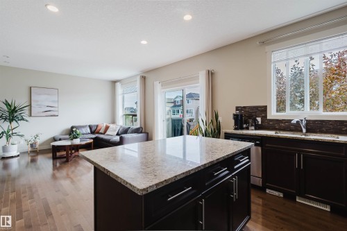 Kitchen island with light-toned countertop, dark wood-finish cabinetry, and stainless steel hardware - 3843 Agar Green Sw, Edmonton, AB - Indoor