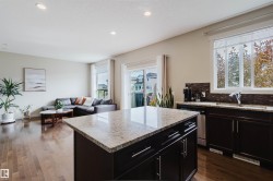 Kitchen island with light-toned countertop, dark wood-finish cabinetry, and stainless steel hardware - 