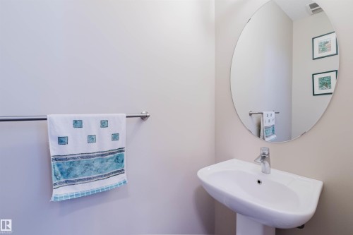 Pedestal sink with chrome faucet, complemented by an oval wall-mounted mirror - 3843 Agar Green Sw, Edmonton, AB - Indoor Photo Showing Bathroom