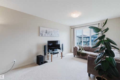Wall-to-wall carpeting with light-toned walls, featuring a large window with vertical blinds, and a ceiling-mounted light fixture - 3843 Agar Green Sw, Edmonton, AB - Indoor