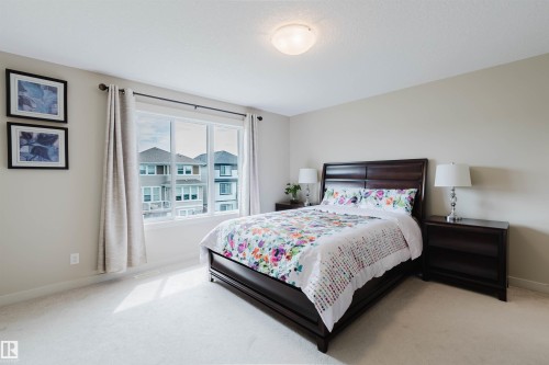 Expansive window, neutral wall paint, light-colored carpeting, flush mount ceiling light, and dark wood-finish bed frame - 3843 Agar Green Sw, Edmonton, AB - Indoor Photo Showing Bedroom