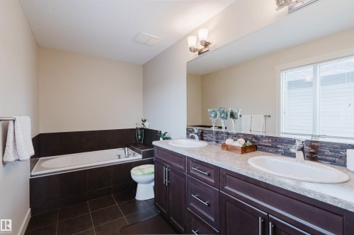 Dual vanity with integrated sinks, dark wood-finish cabinetry, and a full-width mirror - 3843 Agar Green Sw, Edmonton, AB - Indoor Photo Showing Bathroom