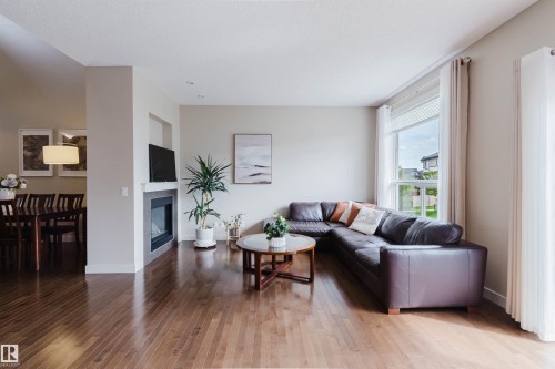 Warm wood-finish flooring throughout, featuring a built-in fireplace with a stone surround - 3843 Agar Green Sw, Edmonton, AB - Indoor Photo Showing Living Room