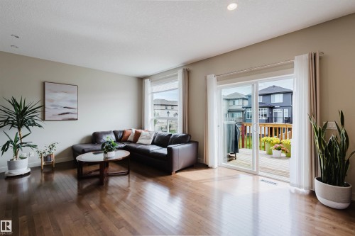 Hardwood-finish flooring, recessed ceiling lighting, large windows with roller shades, and a glass sliding door leading to an outdoor deck - 3843 Agar Green Sw, Edmonton, AB - Indoor Photo Showing Living Room