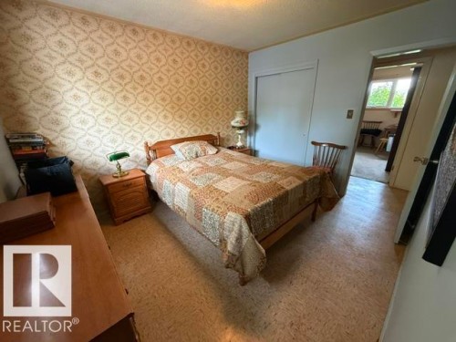 Bedroom featuring patterned wallpaper, neutral flooring, and a built-in closet with sliding doors - 13508 64 Street Nw, Edmonton, AB - Indoor Photo Showing Bedroom