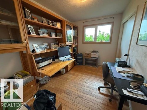 Room featuring extensive built-in wooden cabinetry with glass-fronted sections, integrated desk space, and open shelving - 13508 64 Street Nw, Edmonton, AB - Indoor Photo Showing Office