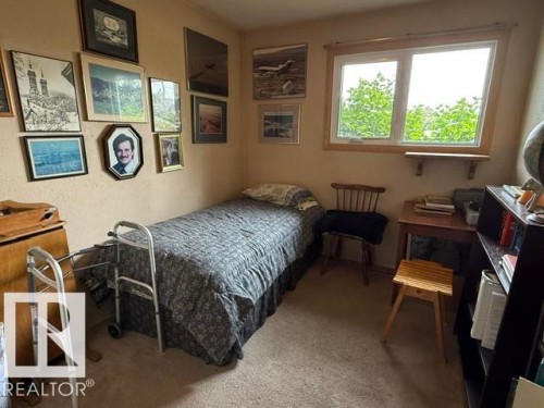Comfortable bedroom featuring a single bed with patterned bedding, wood-finish flooring, and abundant natural light from a large multi-pane window - 13508 64 Street Nw, Edmonton, AB - Indoor Photo Showing Bedroom