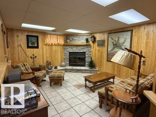 Stone-faced fireplace with a raised hearth, wood paneling, and ceramic tile flooring - 13508 64 Street Nw, Edmonton, AB - Indoor With Fireplace