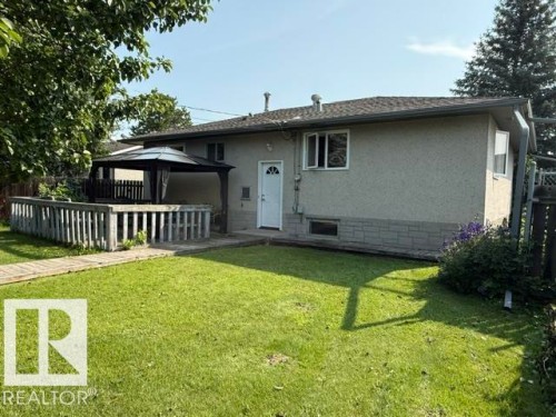 Rear exterior featuring stucco siding with a stone-look foundation, a ground-level patio with a privacy fence, and a gazebo - 13508 64 Street Nw, Edmonton, AB - Outdoor