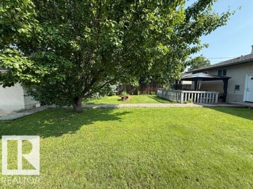 Expansive backyard featuring a large tree, a manicured lawn, a paved patio, and a covered deck with a gazebo - 13508 64 Street Nw, Edmonton, AB - Outdoor