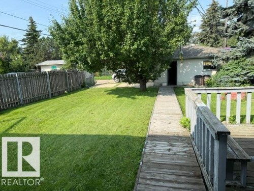 Expansive backyard featuring a large tree, grass lawn, wood fencing, and a wood deck - 13508 64 Street Nw, Edmonton, AB - Outdoor