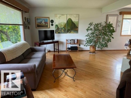 Bright interior space featuring wood-finish flooring, white walls, and prominent window fixtures - 13508 64 Street Nw, Edmonton, AB - Indoor Photo Showing Living Room