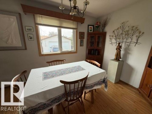 Dining area featuring wood-finish flooring, a wood-trimmed window with blinds, and a built-in corner cabinet - 13508 64 Street Nw, Edmonton, AB - Indoor Photo Showing Dining Room