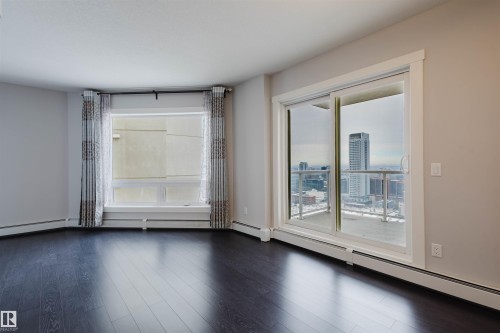 Dark wood-finish flooring with a light gray wall color - #2207 10226 104 St Nw, Edmonton, AB - Indoor Photo Showing Other Room
