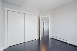 Wood-finish flooring, white walls, white trim, sliding closet doors, and a doorway with a white door - 