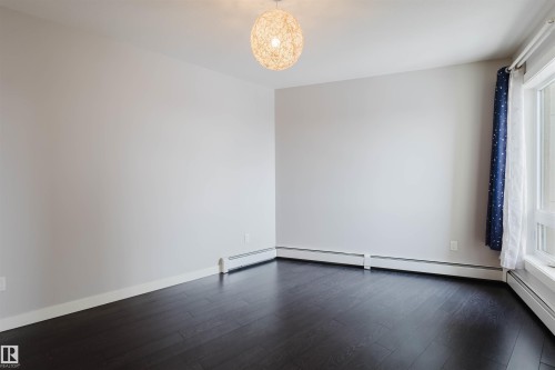 Dark wood-finish flooring with white walls and baseboards - #2207 10226 104 St Nw, Edmonton, AB - Indoor Photo Showing Other Room