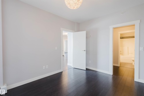 Dark wood-finish flooring with light-toned walls - #2207 10226 104 St Nw, Edmonton, AB - Indoor Photo Showing Other Room