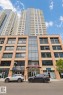 Multi-story building featuring a brick-clad lower facade, a glass and metal mid-section, and a towering light-colored upper structure with numerous balconies - #2207 10226 104 St Nw, Edmonton, AB  - Outdoor With Facade 