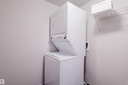 Stackable washer and dryer unit, white wire shelving, and light-toned walls - 
