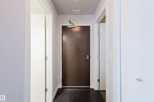 Dark wood-finish flooring, white walls, recessed lighting, and a dark entry door with contemporary hardware - #2207 10226 104 St Nw, Edmonton, AB - Indoor Photo Showing Other Room