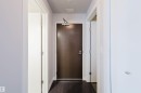 Dark wood-finish flooring, white walls, recessed lighting, and a dark entry door with contemporary hardware - #2207 10226 104 St Nw, Edmonton, AB  - Indoor Photo Showing Other Room 