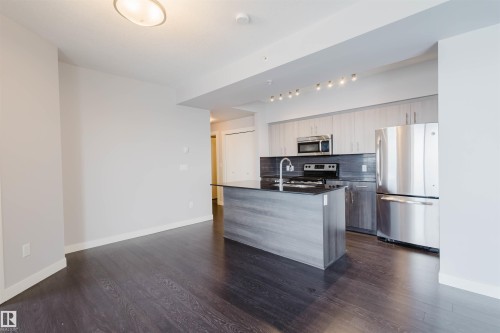 Dark wood-finish flooring throughout - #2207 10226 104 St Nw, Edmonton, AB - Indoor Photo Showing Kitchen With Stainless Steel Kitchen
