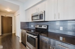 Contemporary kitchen with dark countertops, stainless steel appliances, and a tiled backsplash - 