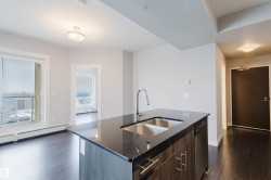 Kitchen island with a double stainless steel sink, gooseneck faucet, and dark stone-finish countertop - 