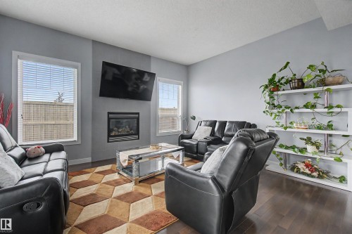 Wood-finish flooring, built-in fireplace, and expansive windows - 1602 Chapman Way Sw, Edmonton, AB - Indoor Photo Showing Living Room With Fireplace