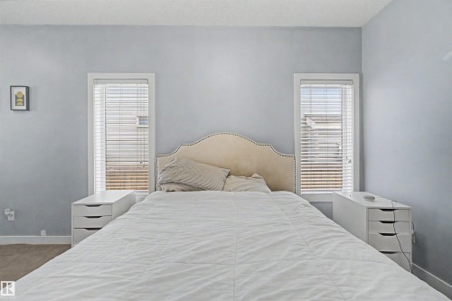 Two windows with blinds, light blue wall paint, and carpeted flooring - 1602 Chapman Way Sw, Edmonton, AB - Indoor Photo Showing Bedroom