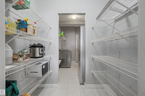 Walk-in pantry with extensive wire shelving, tile flooring, and access to a utility space - 1602 Chapman Way Sw, Edmonton, AB - Indoor With Storage