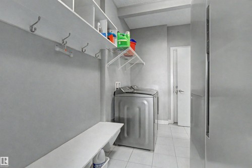 Laundry area with open shelving, wall-mounted hooks, white tile flooring, and a built-in bench - 1602 Chapman Way Sw, Edmonton, AB - Indoor Photo Showing Laundry Room