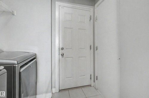 White paneled door, white walls, and light-toned tile flooring - 1602 Chapman Way Sw, Edmonton, AB - Indoor Photo Showing Laundry Room