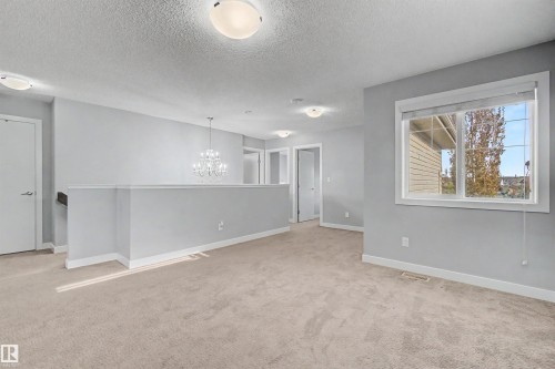 Carpeted flooring, chandelier lighting, recessed lighting, and a large window - 1602 Chapman Way Sw, Edmonton, AB - Indoor Photo Showing Other Room