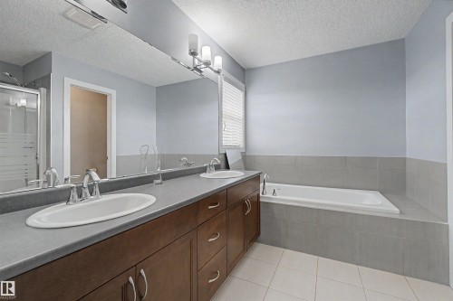 Dual vanity with oval undermount sinks, chrome fixtures, and wood-finish cabinetry - 1602 Chapman Way Sw, Edmonton, AB - Indoor Photo Showing Bathroom