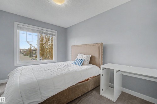 Neutral wall paint, carpet flooring, a large window with white trim, and a ceiling-mounted light fixture - 1602 Chapman Way Sw, Edmonton, AB - Indoor Photo Showing Bedroom