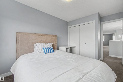 Upholstered headboard with nailhead trim, built-in closet with bi-fold doors, and neutral wall paint - 1602 Chapman Way Sw, Edmonton, AB - Indoor Photo Showing Bedroom