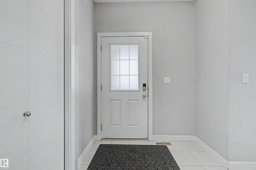 Entryway with white tiled flooring, a white door with frosted glass panels, and light gray wall finishes - 1602 Chapman Way Sw, Edmonton, AB - Indoor Photo Showing Other Room