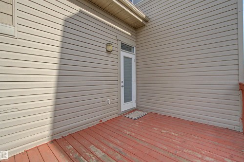 Exterior deck with red-toned wood flooring, light-colored siding, and a glass-paneled door - 1602 Chapman Way Sw, Edmonton, AB - Outdoor With Exterior