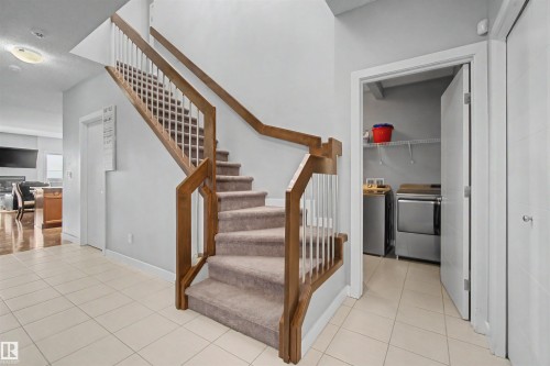 Staircase with wood-finish handrails, carpeted treads, and tiled flooring - 1602 Chapman Way Sw, Edmonton, AB - Indoor Photo Showing Other Room