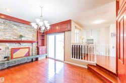 Living area featuring a stone accent wall with a fireplace, cherry wood-finish flooring, built-in shelving, a glass sliding door, and a multi-tiered chandelier - 