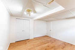 Room featuring wood-finish flooring, white walls, and a drop ceiling - 