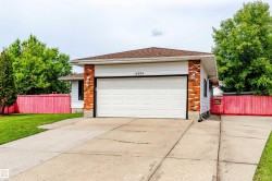 Property exterior featuring a two-car garage, concrete driveway, and brick and siding facade - 