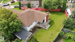Expansive backyard featuring a large concrete patio, mature perimeter trees, and a red-painted fence - 